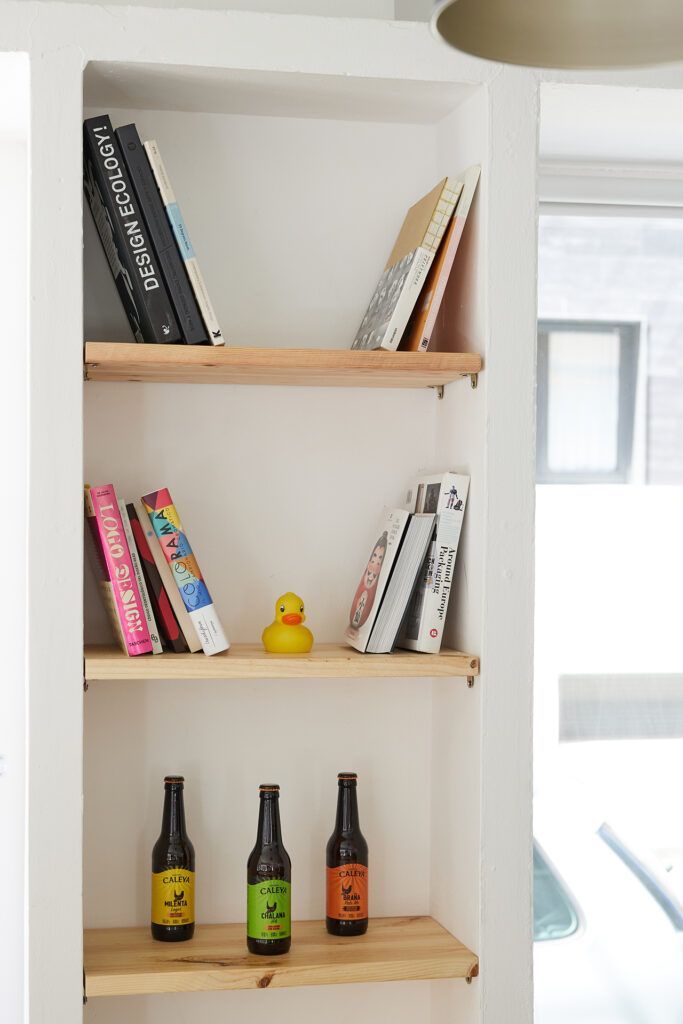 Una foto del local, en este caso, con una librería con libros y unas botellas, en el que está Básico Estudio en Gijón, Asturias.